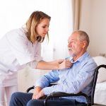 Nurse and senior man in wheelchair during home visit. Nurse and senior man in wheelchair during home visit